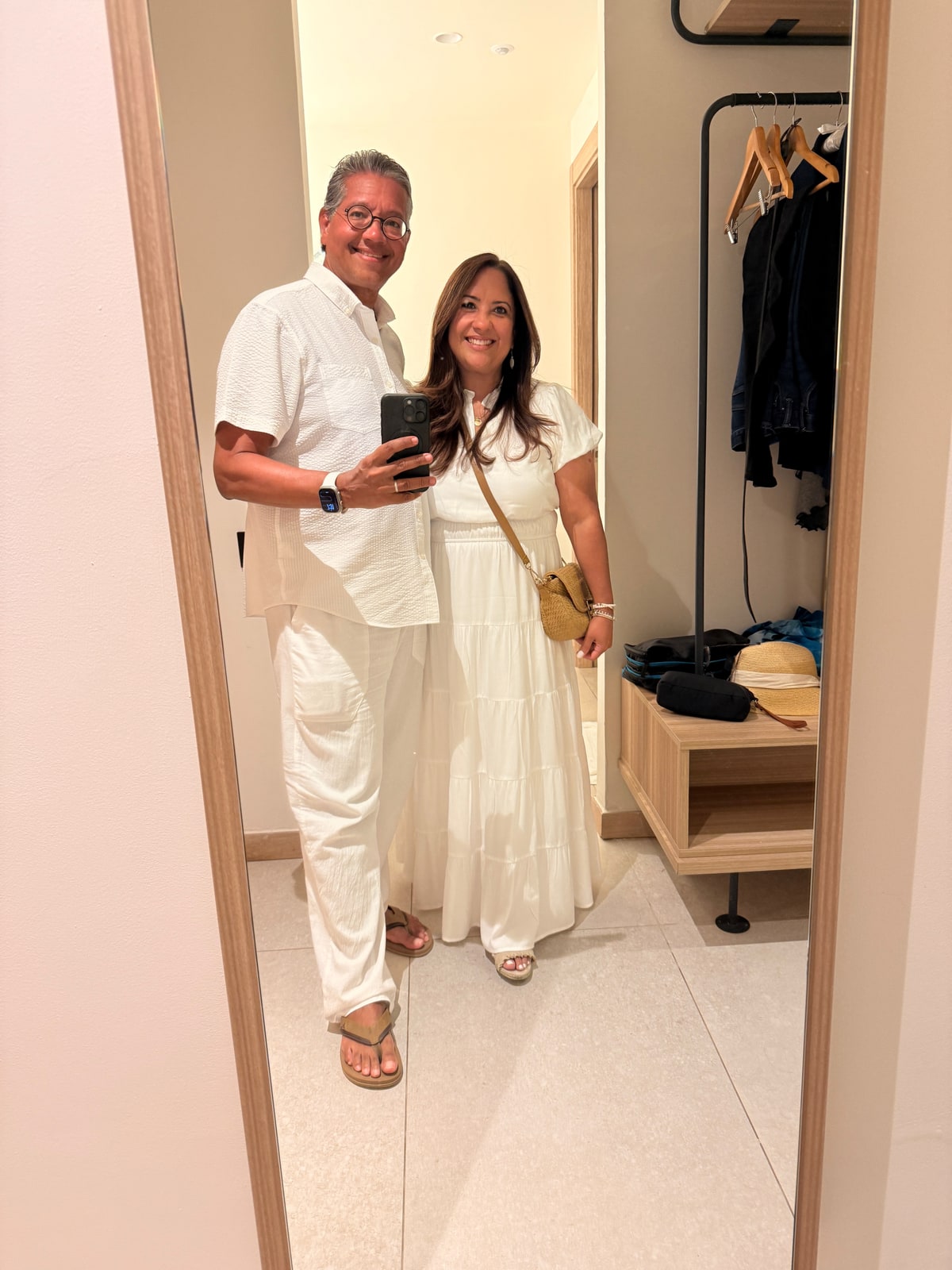 Richie y Niletzy, vestidos de blanco y sonriendo juntos frente al espejo.